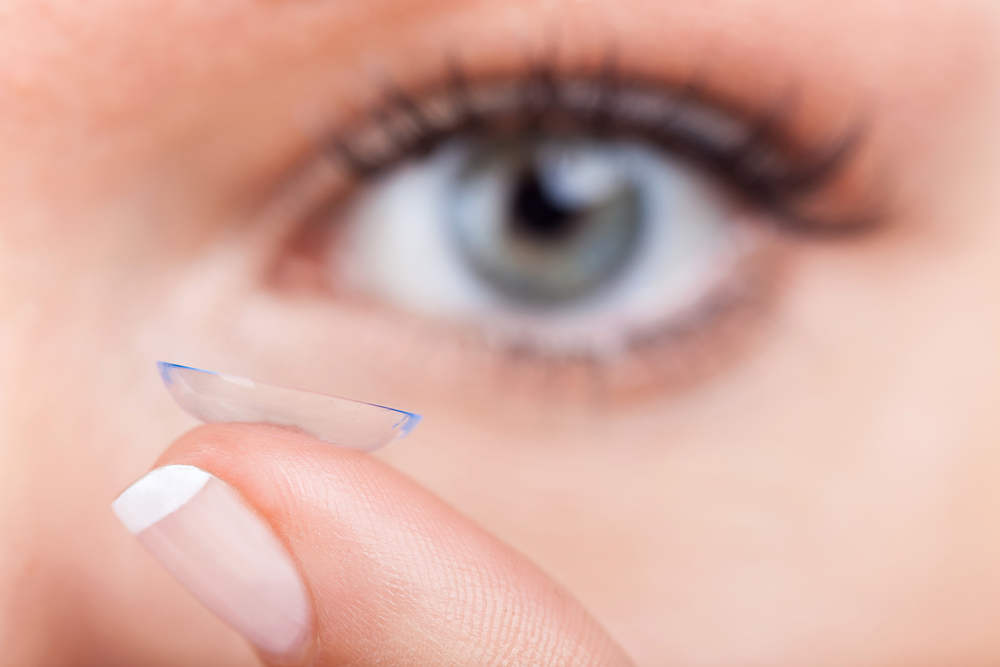 Woman holding contact lens to her eye