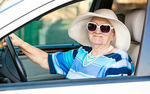 Senior woman in hat and sunglasses in car
