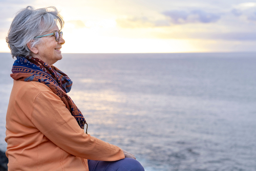 woman sitting with ocean and sunset in background