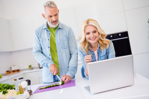 Couple cooking and looking at computer