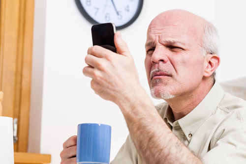 Older man struggling to read phone screen