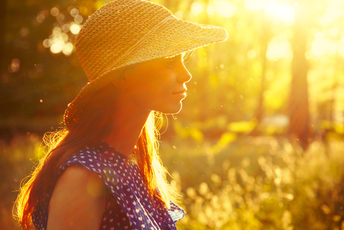 Woman in hat back-lit by sunset